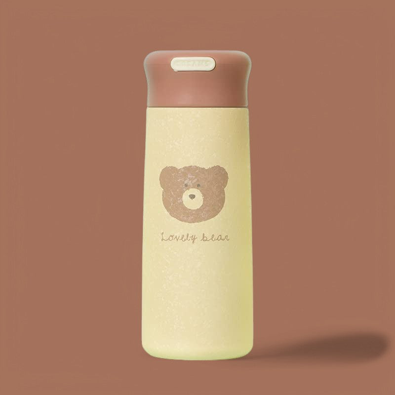Cream-colored stainless steel insulated water bottle for kids with a brown cap, featuring a cute 'lovely bear' cartoon design. Keeps drinks hot or cold. Ideal for school or travel from uSmile.toys." WWW.USMILE.TOYS