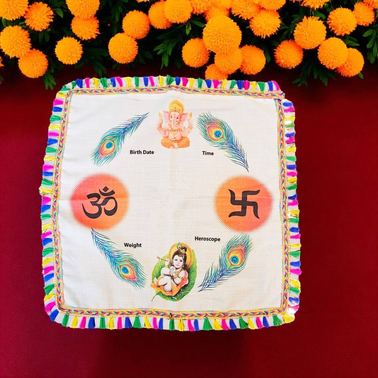 Decorative cloth with symbols and designs on a red background with marigold flowers.