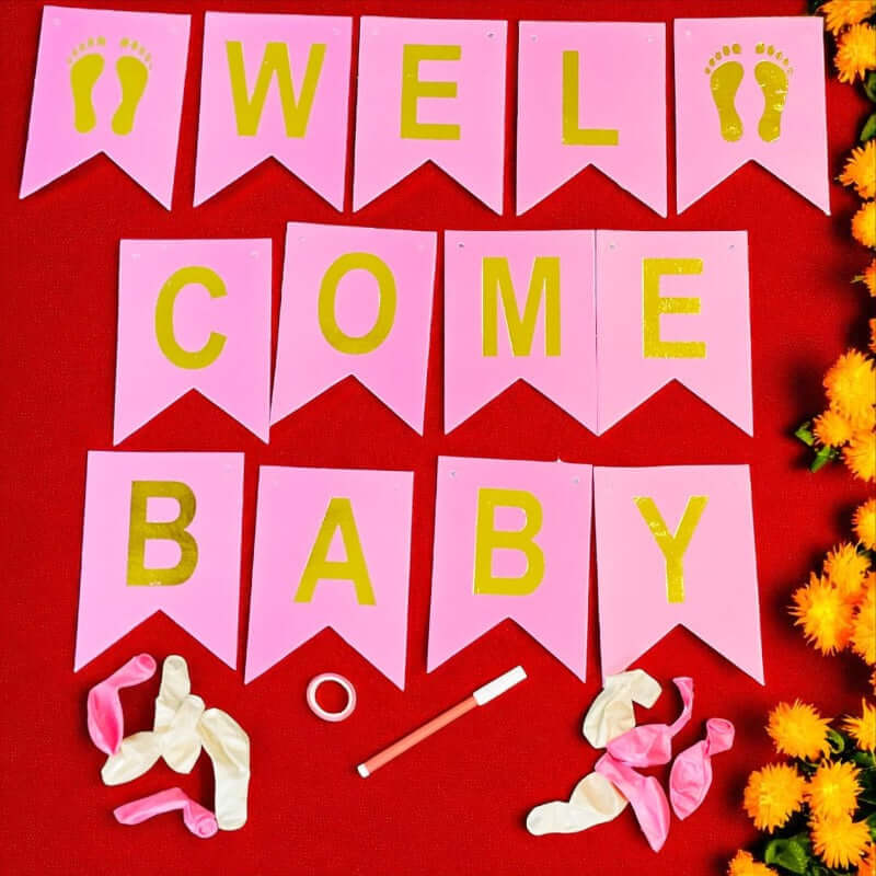 Pink 'Welcome Baby' banner with yellow text on a red background, surrounded by baby shower decorations.
