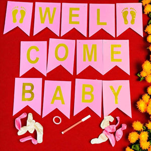 Pink 'Welcome Baby' banner with yellow text on a red background, surrounded by baby shower decorations.