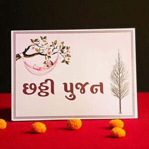 Card with a baby in a hammock and tree design, placed on a red surface with decorative items.