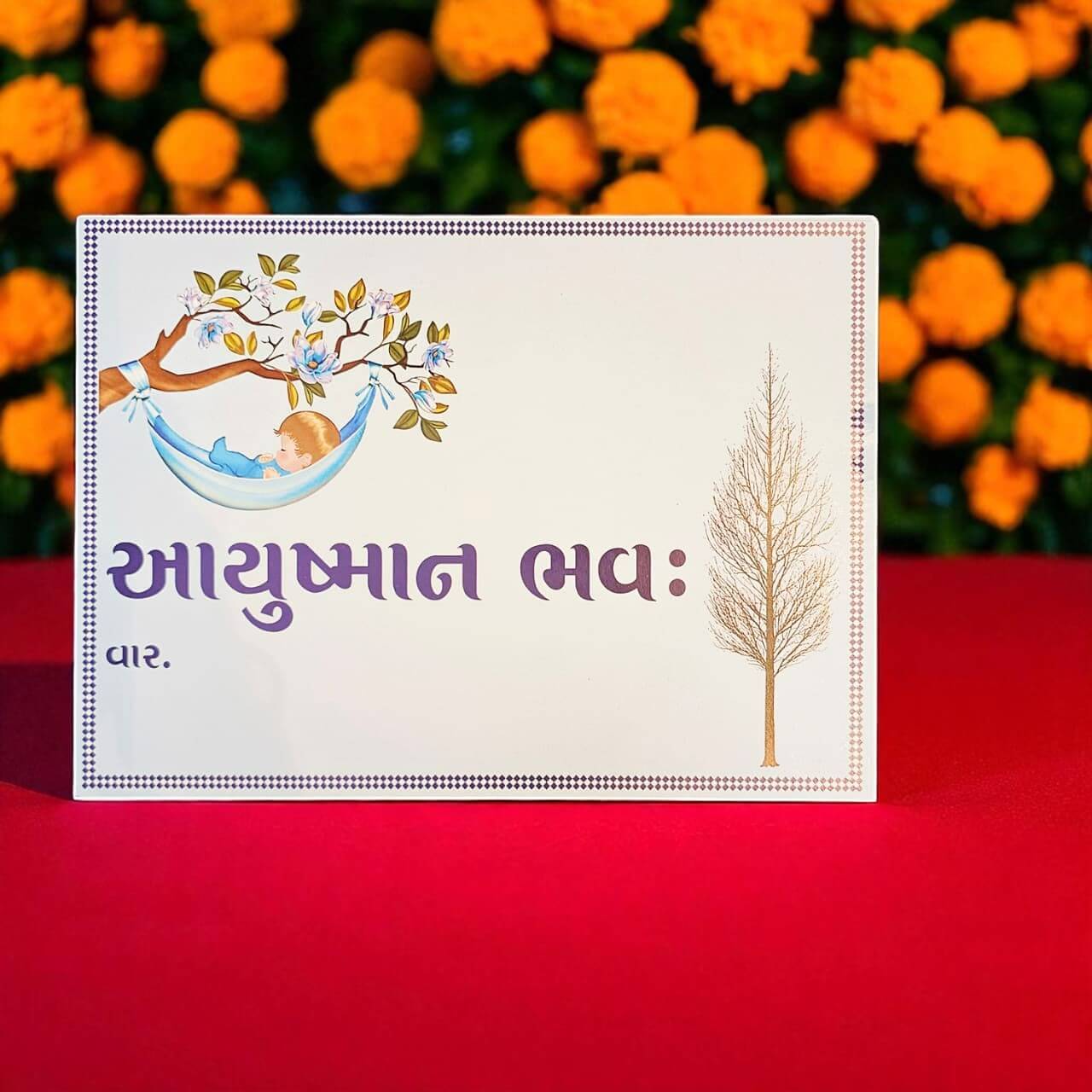 Card with a child in a hammock and tree design on a red background with marigold flowers.