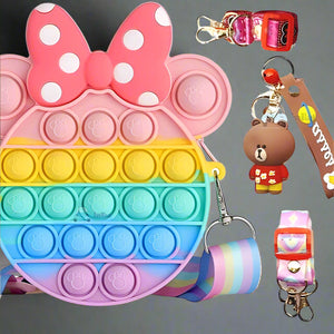 Usmile Toys Kids' rainbow-colored Pop It fidget crossbody bag with a large pink polka-dot bow, shown with fun keychains including a brown bear and a pink unicorn." www.usmile.toys