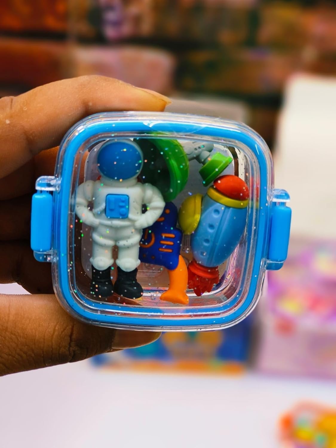 Fun, colorful erasers in animal and space shapes, including a green alien, white astronaut, and red rocket.            www.usmile.toys