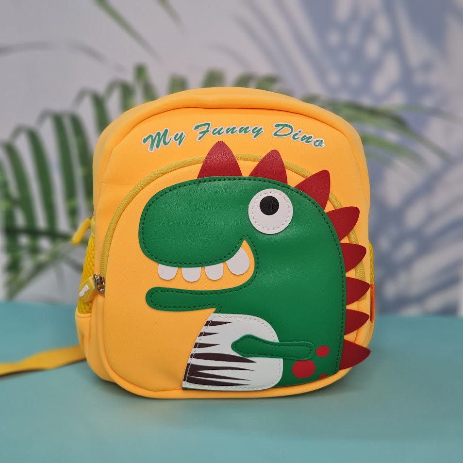 Small, yellow backpack for children featuring a large green dinosaur applique with red spikes and white teeth on the front pocket. Above the dinosaur is embroidered yellow cursive text that reads "My Funny Dino". The backpack has yellow straps and yellow mesh side pockets