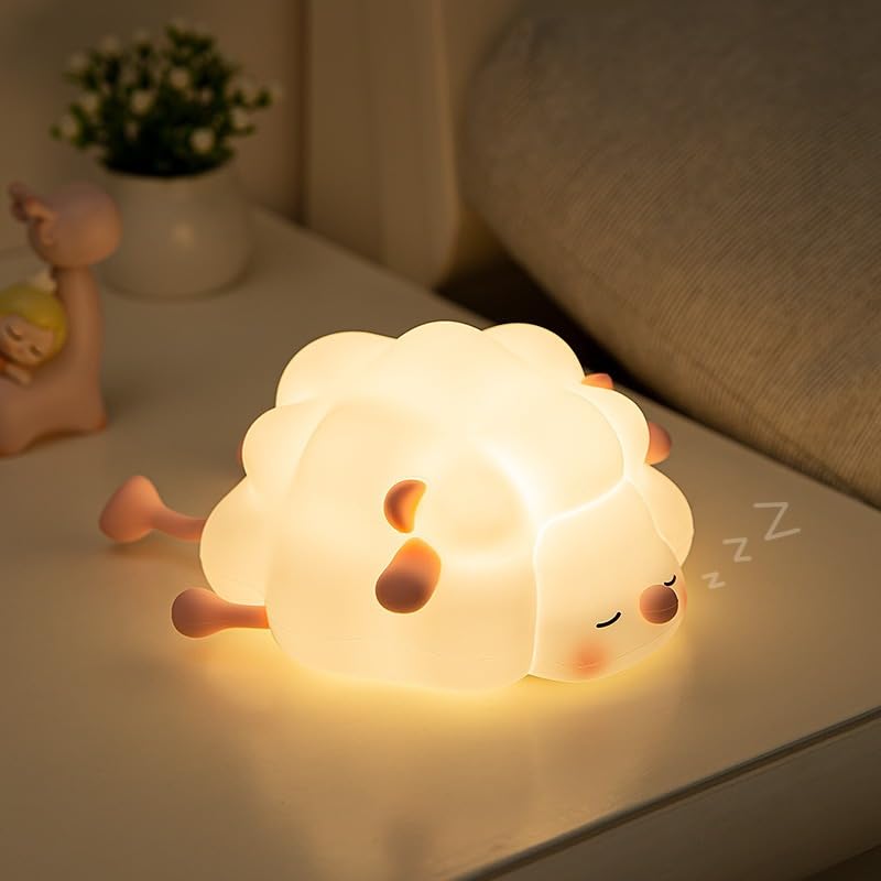 Adorable glowing white silicone night lamp for kids, shaped like a little sleeping sheep with closed eyes and a peaceful expression, resting on a white surface. Ideal for a calming bedtime ambiance from uSmile.toys." www.usmile.toys