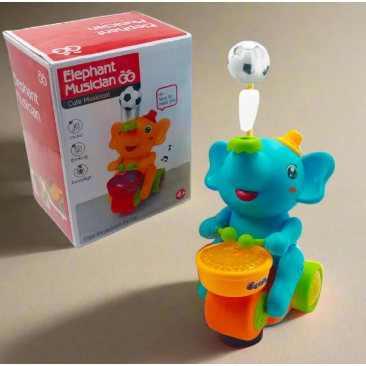 Blue elephant musician toy by Usmile Toys, riding a scooter and balancing a soccer ball on its trunk, with its product box in the background." www.usmile.toys