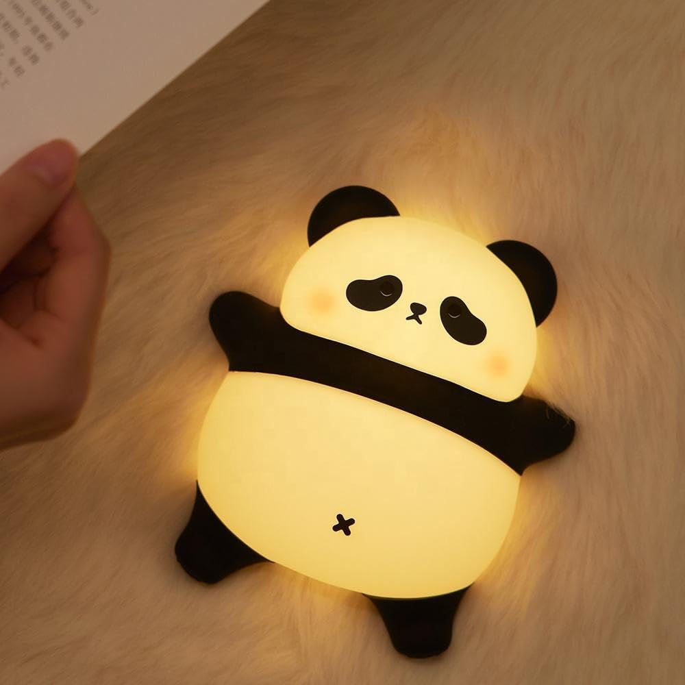 Adorable glowing white and black silicone night lamp for kids, shaped like a cute lying panda, illuminating a surface. Ideal for a comforting and soft light in a child's bedroom from uSmile.toys." www.usmile.toys
