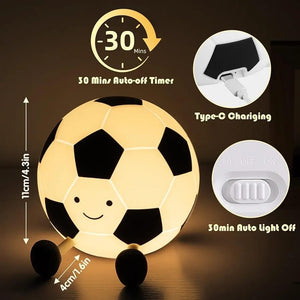 Adorable glowing white and black silicone night lamp for kids, shaped like a soccer ball (football) with a friendly smiley face and small legs, resting on a surface. Ideal for a sports-themed bedroom from uSmile.toys." www.usmile.toys