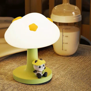 Cute green and white silicone bedside table lamp for kids, with a mushroom-shaped top and a small 'PoPo Panda' figurine sitting at its base. Provides a gentle glow. Ideal for a child's bedroom from uSmile.toys." www.usmile.toys