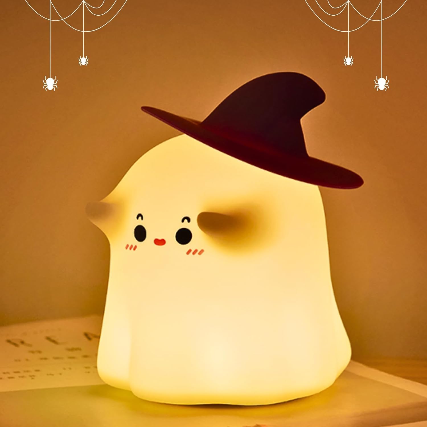 Adorable glowing white silicone night lamp for kids, shaped like a cute ghost wearing a black witch's hat, with subtle facial features. Provides a soft, comforting light. From uSmile.toys." www.usmile.toys