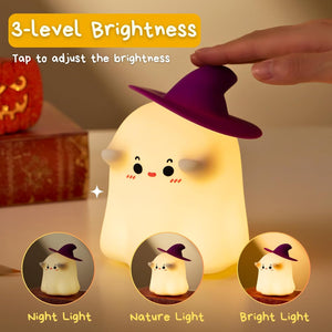 Adorable glowing white silicone night lamp for kids, shaped like a cute ghost wearing a black witch's hat, with subtle facial features. Provides a soft, comforting light. From uSmile.toys." www.usmile.toys