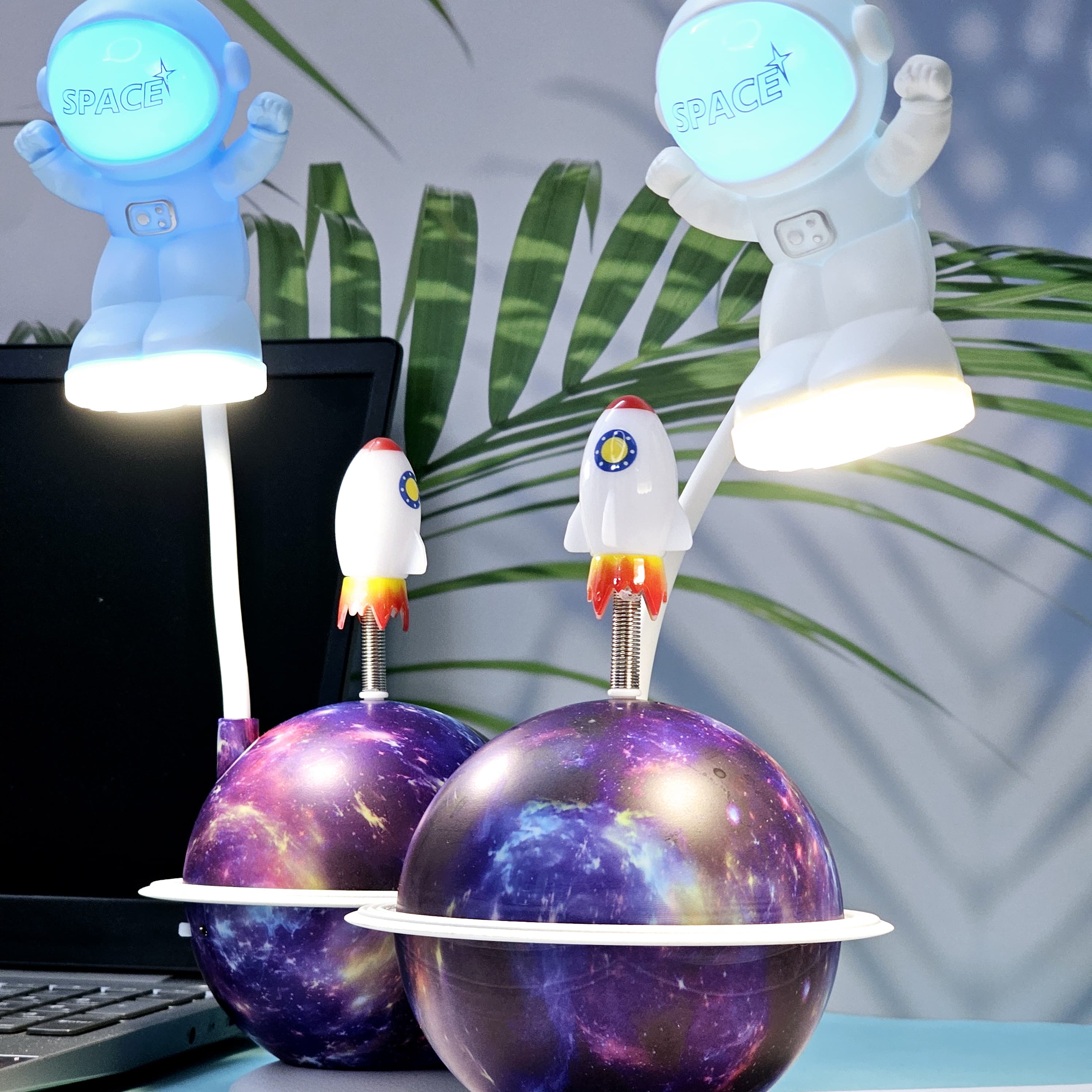 "Close-up of a Usmile Toys creative astronaut lamp, showing its white astronaut figure, flexible arm, and a striking purple and blue glowing planet base with a rocket fin." www.usmile.toys