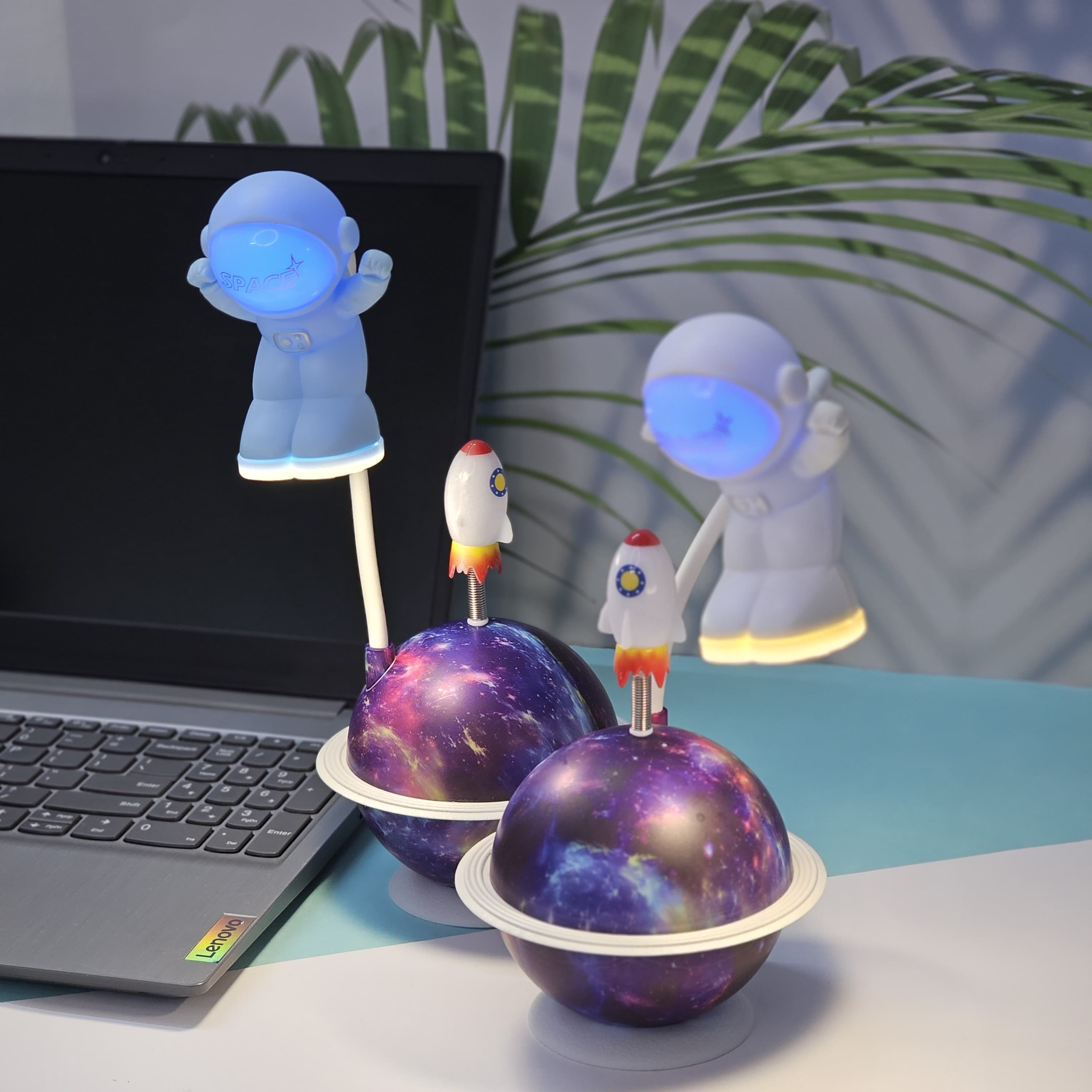 "Close-up of a Usmile Toys creative astronaut lamp, showing its white astronaut figure, flexible arm, and a striking purple and blue glowing planet base with a rocket fin."