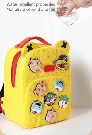 Front view of a fun, customizable silicone waterproof school bag for children, featuring a vibrant yellow color and various playful detachable badges like a rainbow, sun, and animals, ideal for kindergarten or primary school students from Usmile Toys.www.usmile toys