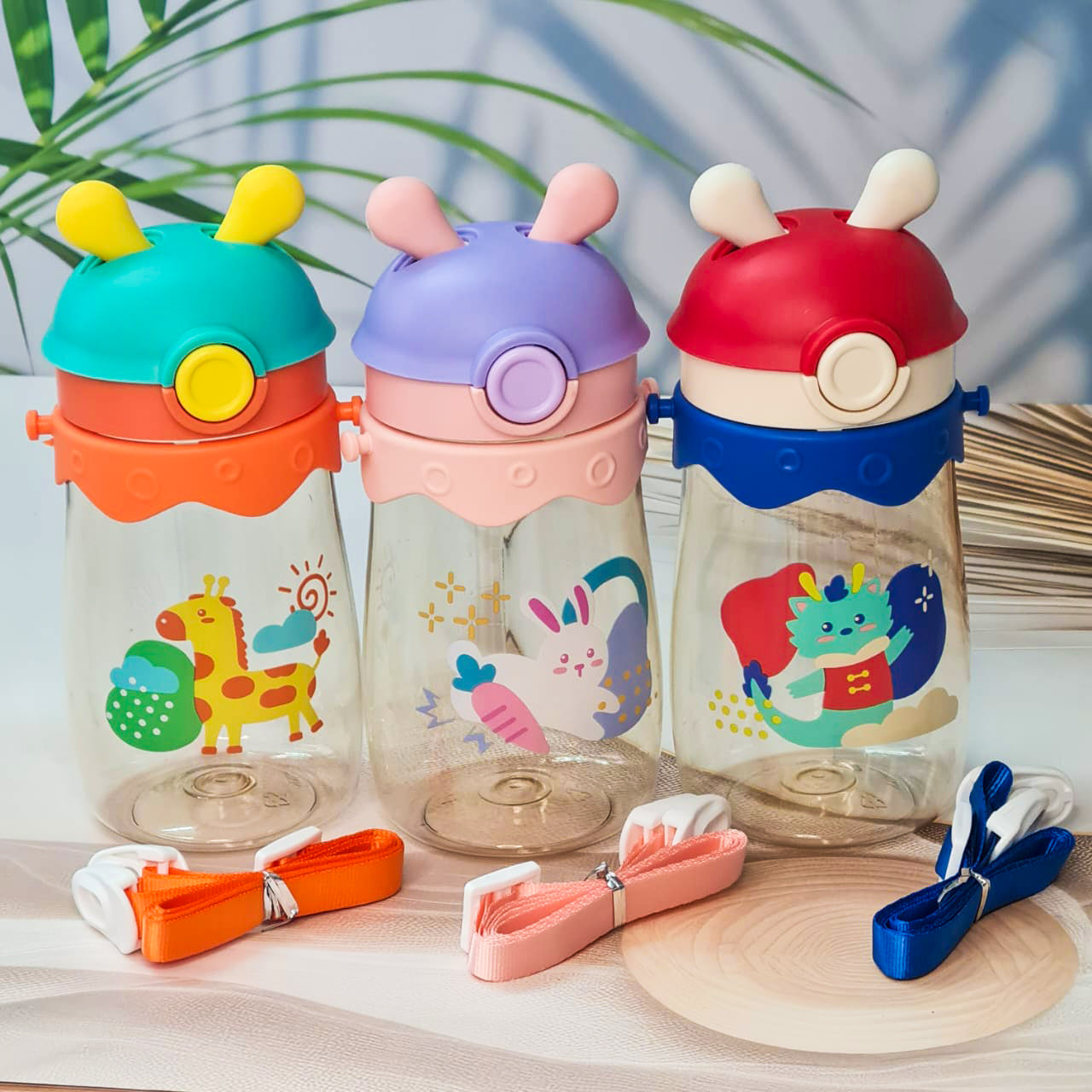 Set of three colorful kids water bottles with cute animal prints, featuring bunny, giraffe, and dragon designs. Each bottle includes a playful lid with 3D cartoon ears and comes with a matching strap for easy carrying. These BPA-free, leak-proof bottles are ideal for school, travel, and outdoor use—perfect addition to kids stationery and daily essentials