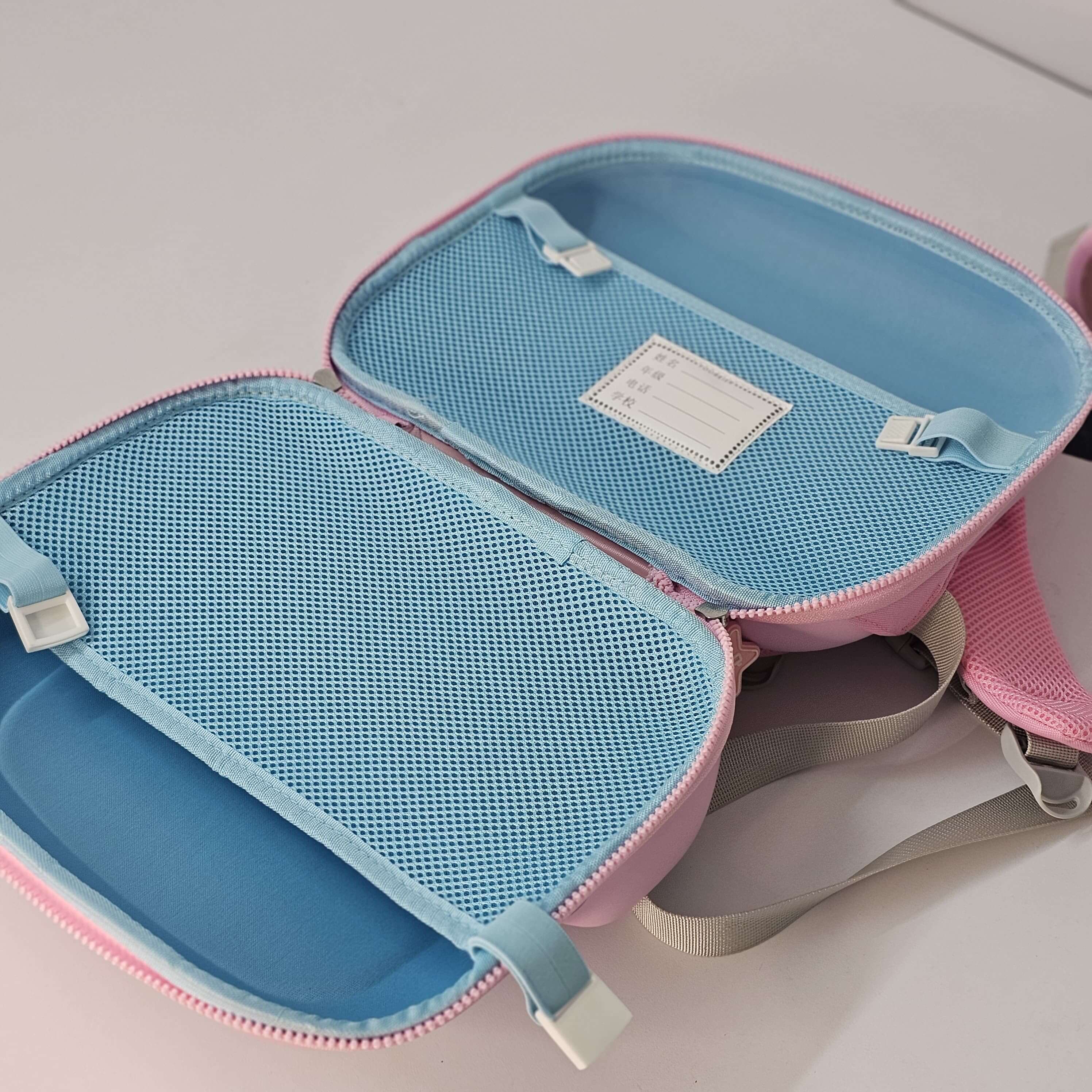 Blue and pink travel pouch with mesh compartments on a light gray background