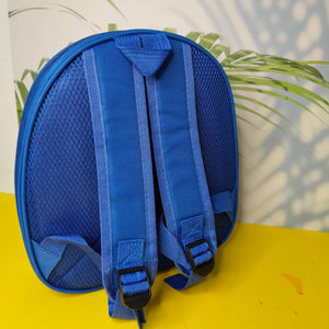 Blue backpack on a yellow surface with a blurred green plant in the background