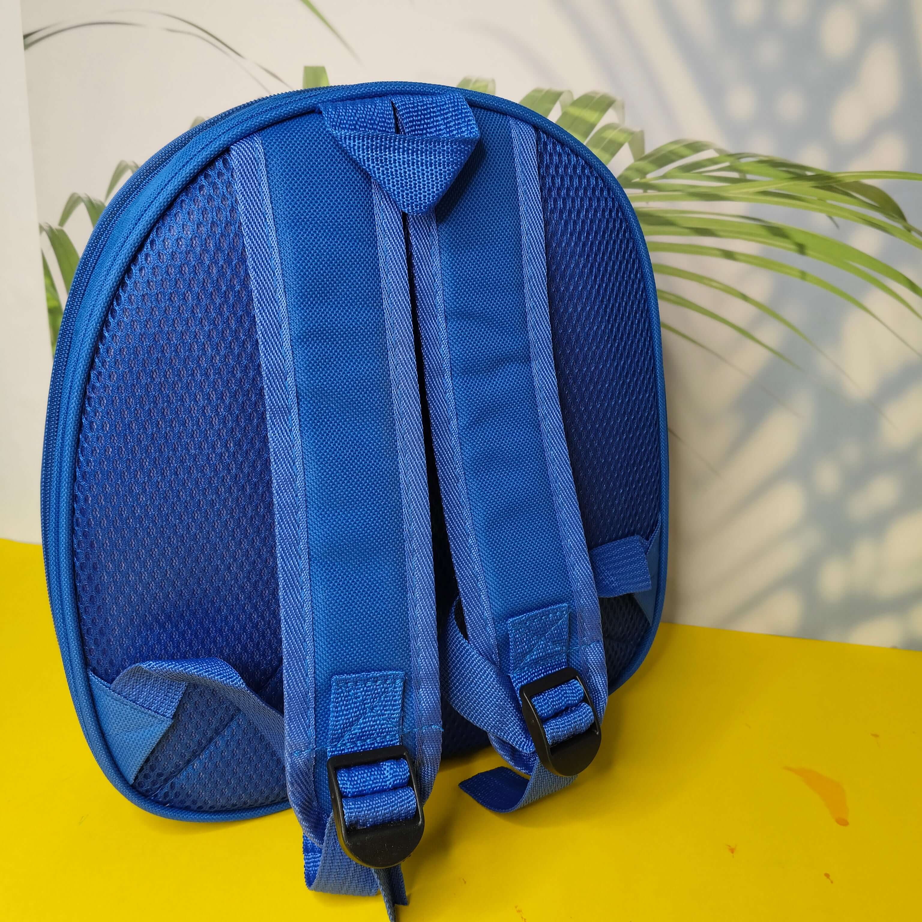 Blue backpack on a yellow surface with a blurred green plant in the background