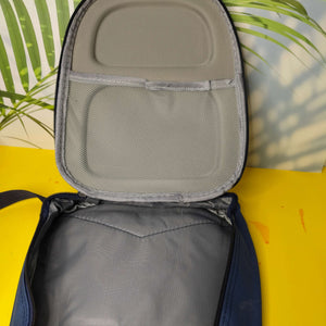 Open gray backpack with a yellow surface and green leaves in the background