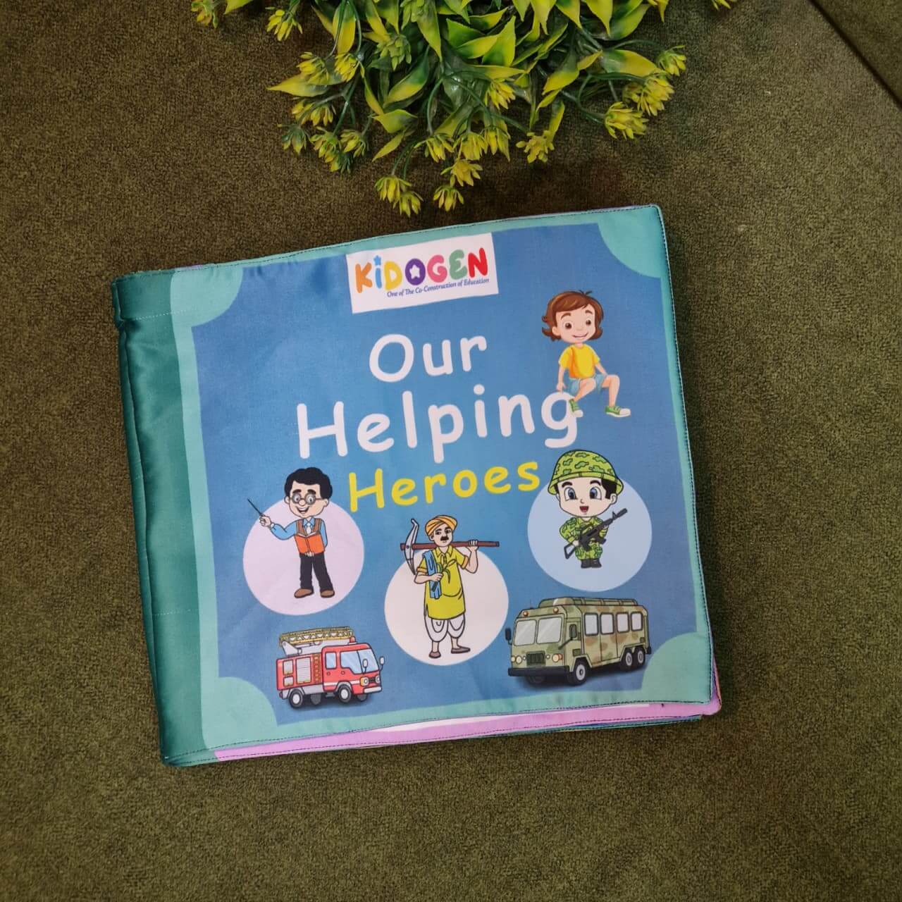 An open "Our Helping Heroes" fabric book by Kidogen, displaying pages about "Police Officers" and "Doctors and Nurses" with illustrations of community helpers and descriptive text.