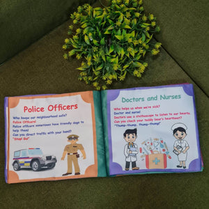 An open "Our Helping Heroes" fabric book by Kidogen, displaying pages about "Police Officers" and "Doctors and Nurses" with illustrations of community helpers and descriptive text.