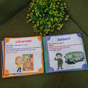 Our Helping Heroes" fabric book by Kidogen, featuring illustrations of a teacher, a farmer, a soldier, a fire truck, and a military vehicle, with the brand logo.