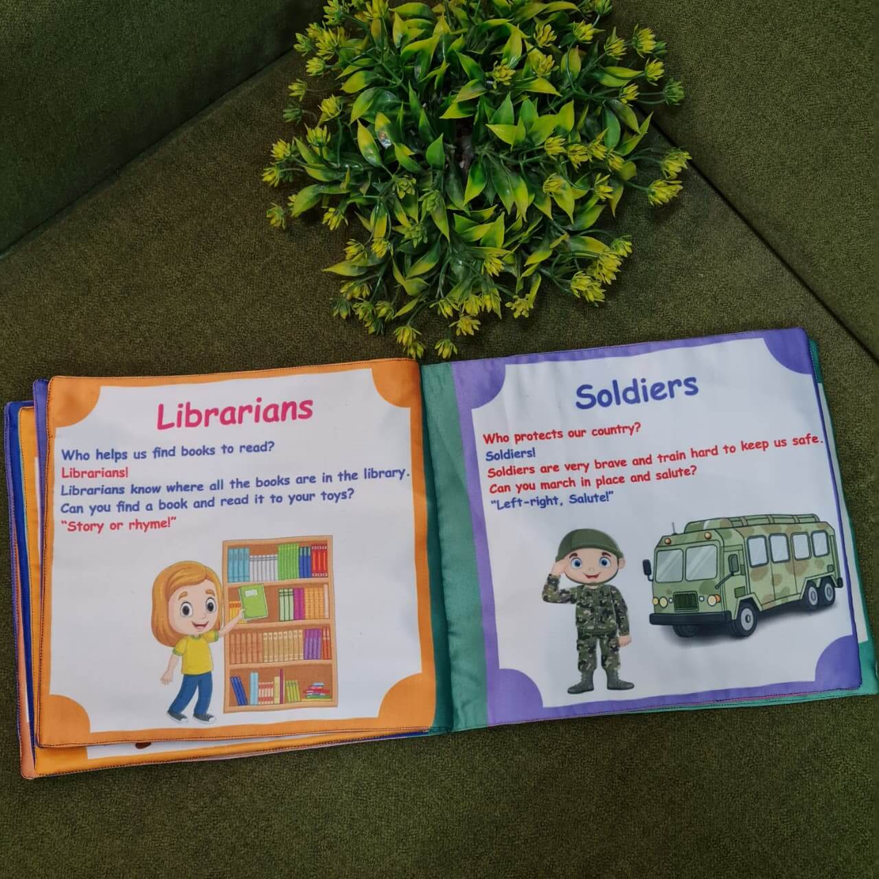 Our Helping Heroes" fabric book by Kidogen, featuring illustrations of a teacher, a farmer, a soldier, a fire truck, and a military vehicle, with the brand logo.