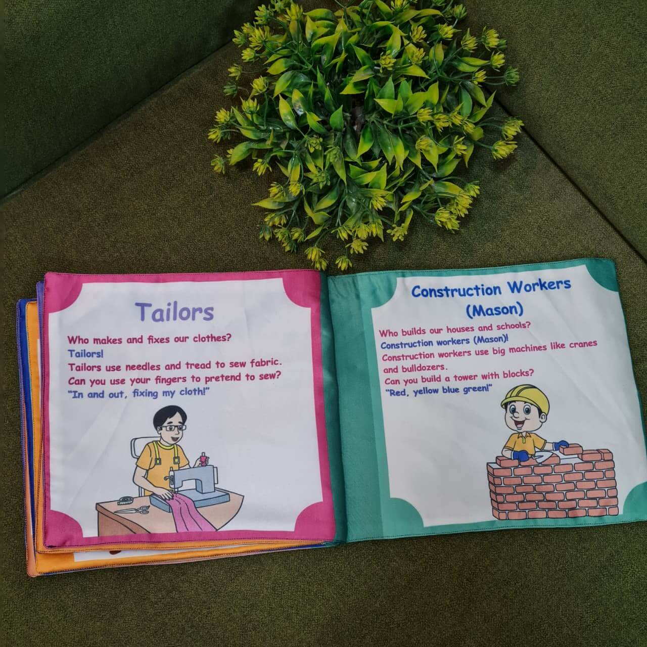 Our Helping Heroes" fabric book by Kidogen, featuring illustrations of a teacher, a farmer, a soldier, a fire truck, and a military vehicle, with the brand logo.