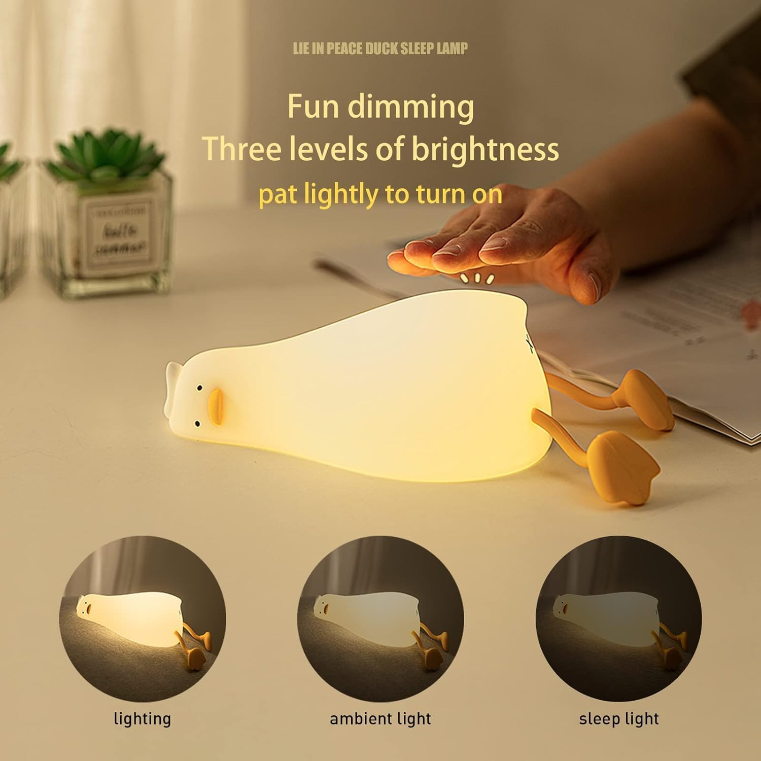 dorable glowing white silicone night lamp for kids, shaped like a little duck lying flat with orange feet and beak, resting on a white surface next to a book. Ideal for a calming bedroom ambiance from uSmile.toys." www,usmile.toys