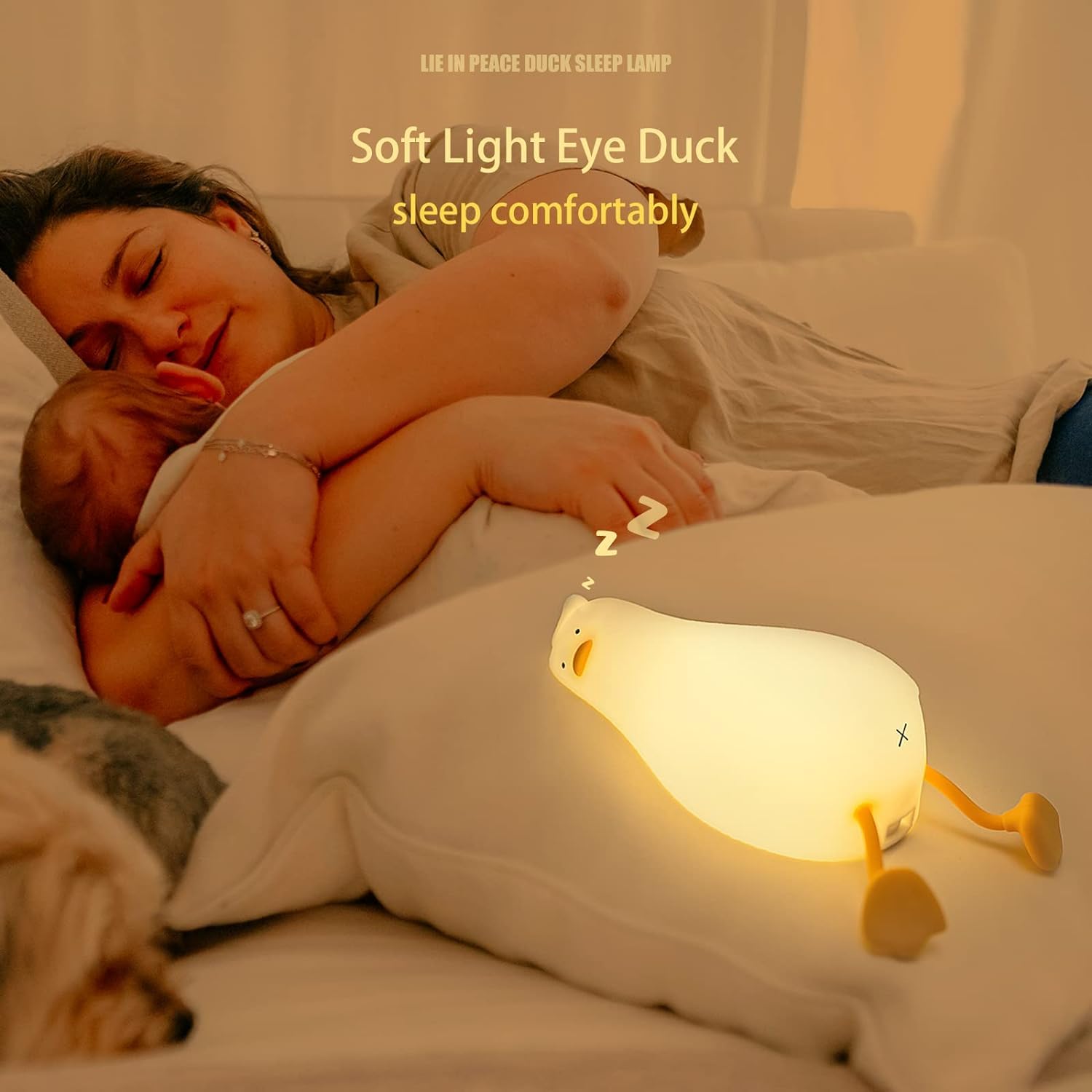 dorable glowing white silicone night lamp for kids, shaped like a little duck lying flat with orange feet and beak, resting on a white surface next to a book. Ideal for a calming bedroom ambiance from uSmile.toys." www,usmile.toys