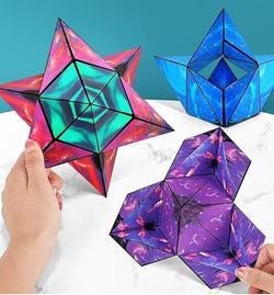 A photo of a boxed product called the “Changeable Magnetic Magic Cube.” The cube is displayed inside a unique packaging that emphasizes its geometric, triangular folding structure. The visible part of the cube has a vibrant, abstract blue design resembling swirling ocean or sky patterns. The box features various marketing phrases. The front side displays the name in bold white font: “Magic Cube,” with "Changeable" in red and "magnetic" in blue, highlighting its changeable and magnetic nature. The right side