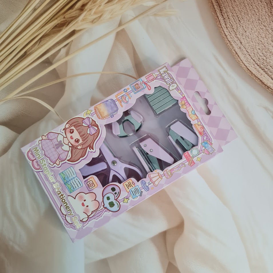Adorable 9-piece Kawaii mini stationery gift set in pastel purple theme, perfect for school kids and return gift ideas – includes stapler, staple remover, hole puncher, tape holder with tape roll, sharpener, scissor, and a box of staples. Packaged in a beautifully designed cartoon-themed gift box with cute illustrations and soft pink-purple tones. Ideal for girls aged 5 and above who love fun and functional stationery items – available at U Smile Toys India