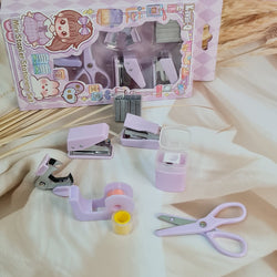 Adorable 9-piece Kawaii mini stationery gift set in pastel purple theme, perfect for school kids and return gift ideas – includes stapler, staple remover, hole puncher, tape holder with tape roll, sharpener, scissor, and a box of staples. Packaged in a beautifully designed cartoon-themed gift box with cute illustrations and soft pink-purple tones. Ideal for girls aged 5 and above who love fun and functional stationery items – available at U Smile Toys India