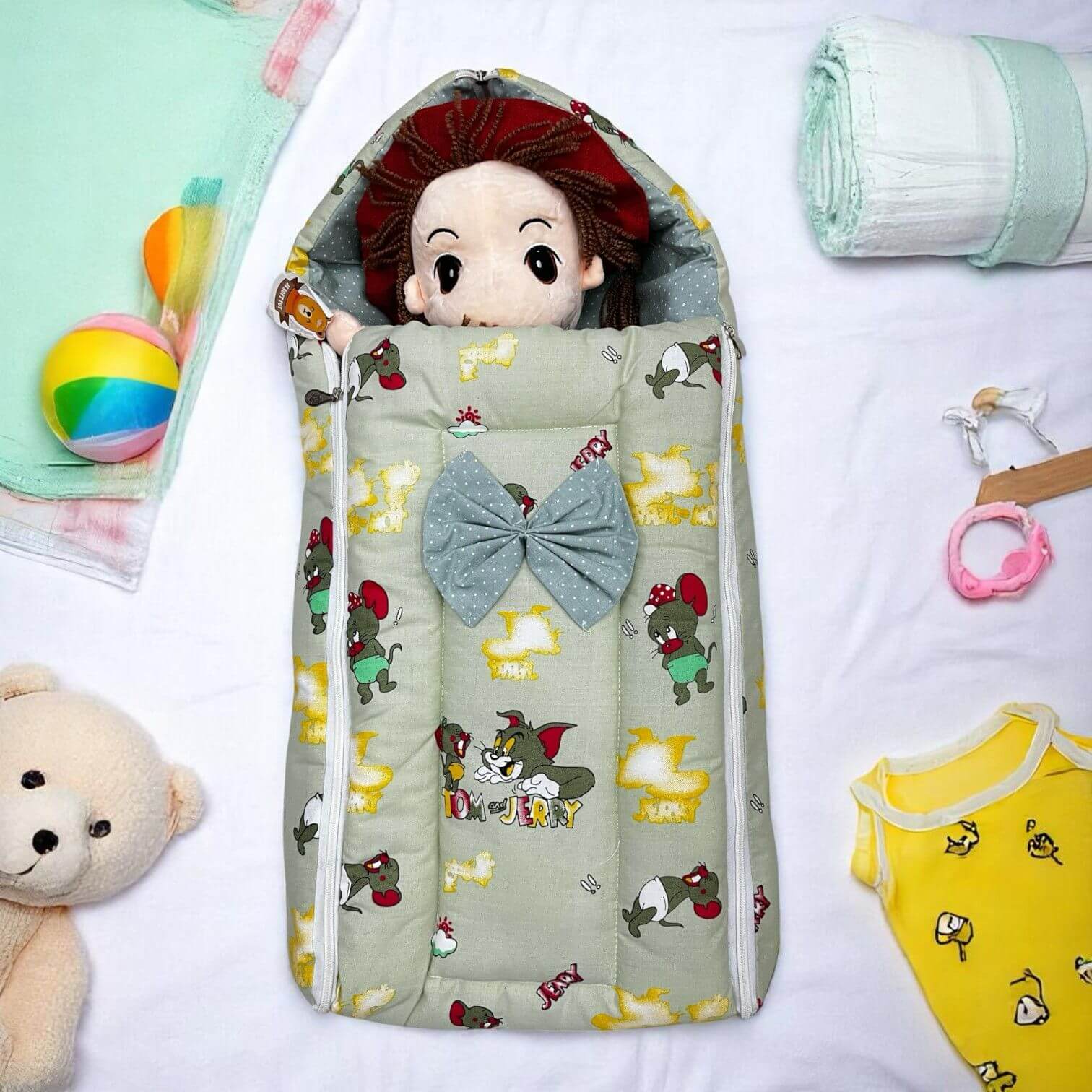 Newborn baby sleeping bag in light green with Tom and Jerry cartoon prints, featuring a cute bow detail. This soft and comfortable sleep sack is ideal for safe and cozy infant sleep, suitable for baby boys and girls. www.usmile.com