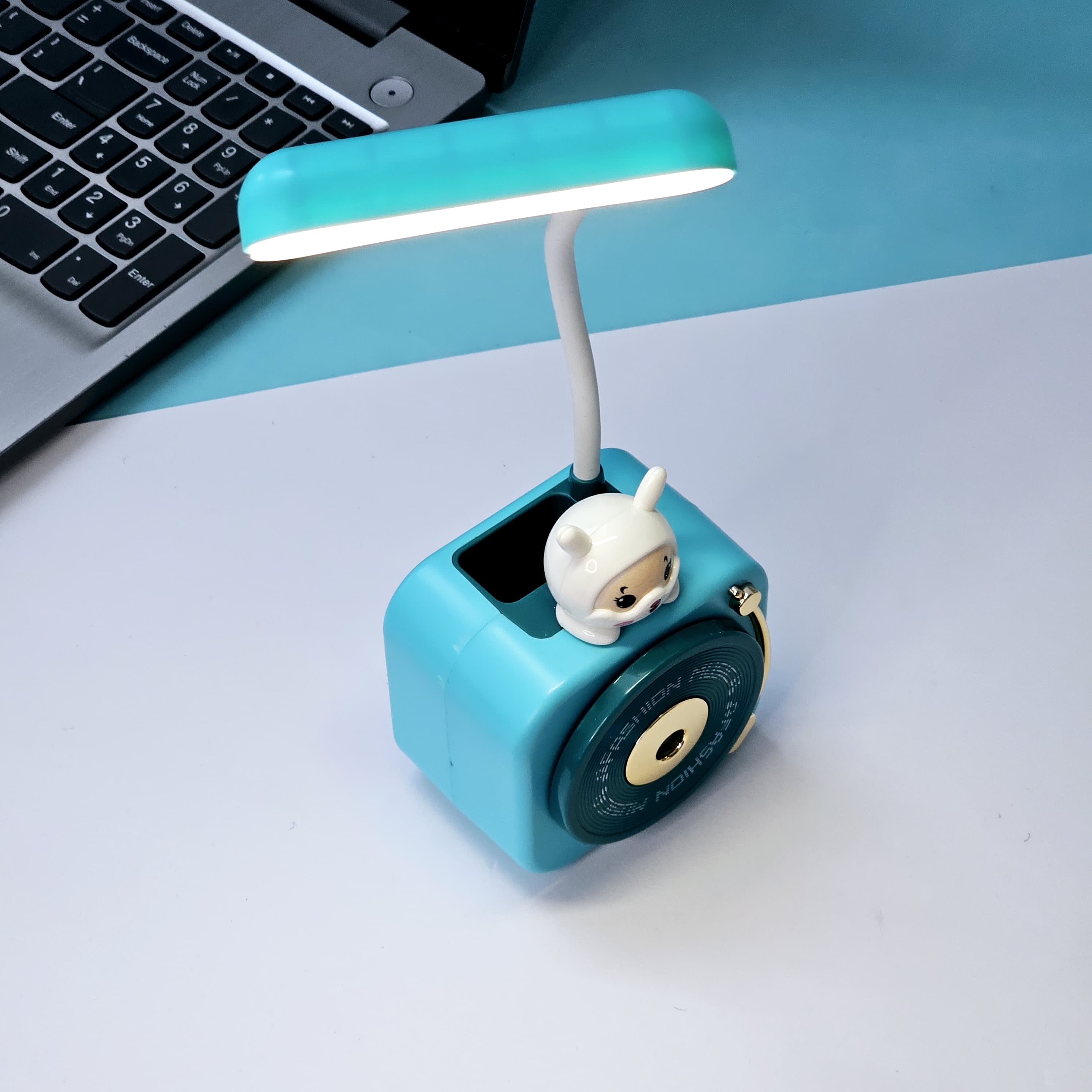 Compact Usmile Toys LED desk lamp with a built-in pencil sharpener and pen holder, perfect for students and kids. This space-saving teal plastic desk light offers bright illumination for reading and drawing, helping children stay organized." www.usmile.toys