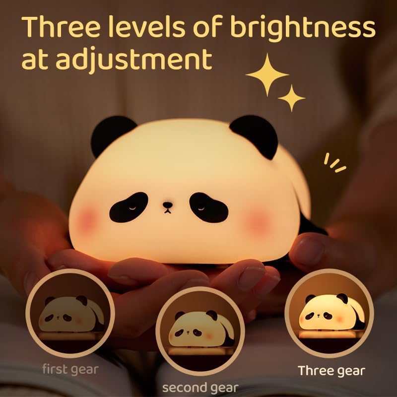 Adorable glowing white and black silicone night lamp for kids, shaped like a cute lying flat panda, resting on green grass against a blue sky. Perfect for a calming bedroom ambiance from uSmile.toys." www.usmile.toys