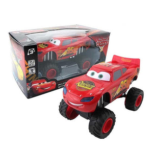 Red toy car with large wheels next to its packaging on a white background