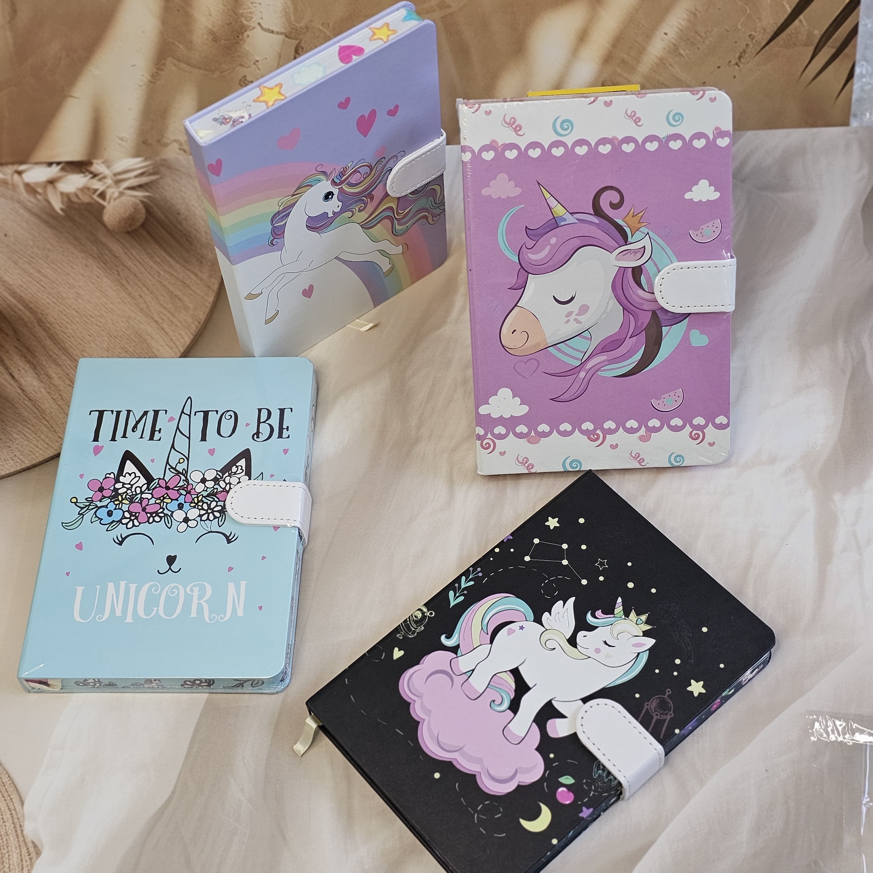 Set of four small unicorn-themed notebook diaries for kids, each with a lock, displayed on a textured surface." www.usmile.toys