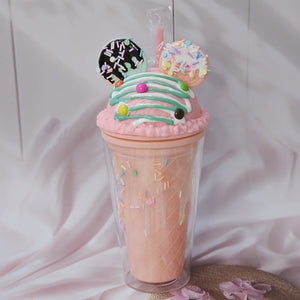 Two adorable Usmile Toys novelty tumblers, one pink and one lime green, each topped with a playful 'ice cream' lid decorated with colorful sprinkles and chocolate drizzle, complete with a straw and an Oreo-shaped charm. Perfect for kids' drinks and adding fun to everyday hydration." www.usmile.toys